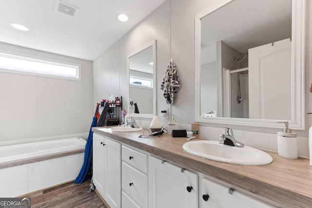 full bathroom with double vanity, wood finished floors, a sink, and visible vents