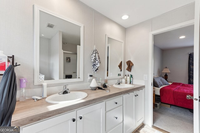 ensuite bathroom with double vanity, ensuite bath, visible vents, and a sink