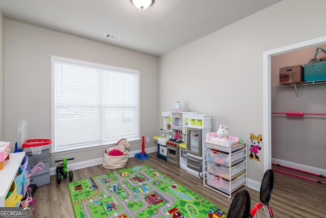 rec room with dark wood-type flooring, visible vents, and baseboards