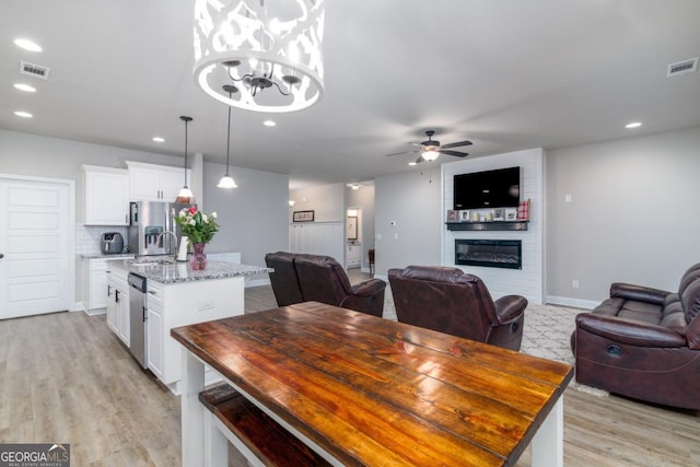 dining space featuring a large fireplace, light wood-style flooring, visible vents, and recessed lighting