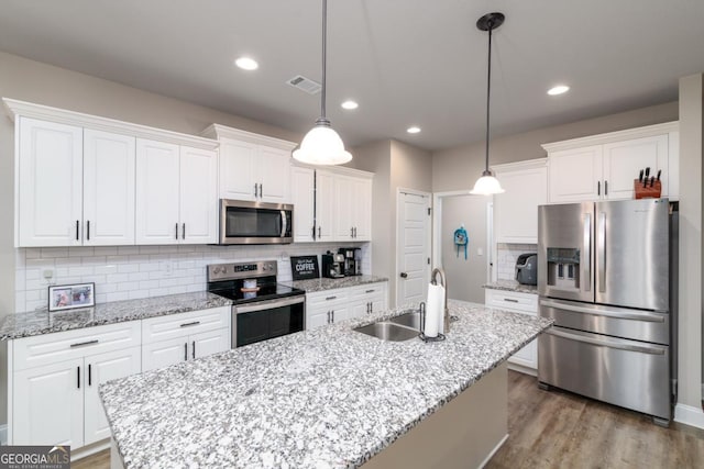 kitchen with white cabinetry, appliances with stainless steel finishes, a sink, and decorative light fixtures