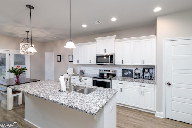 kitchen featuring stainless steel appliances, white cabinetry, hanging light fixtures, and a sink