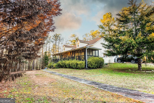 view of side of home with a sunroom and a lawn