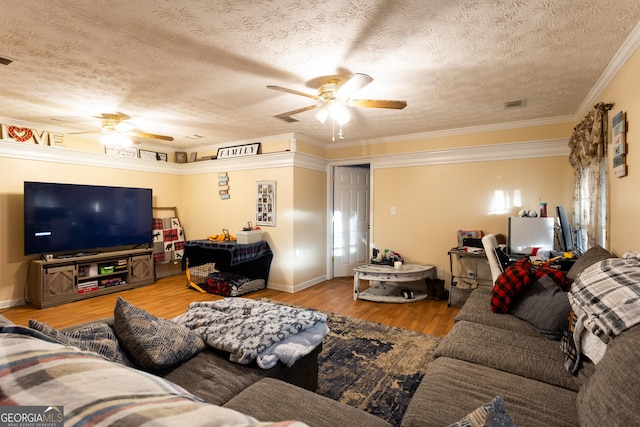 living area with wood finished floors, visible vents, ornamental molding, ceiling fan, and a textured ceiling