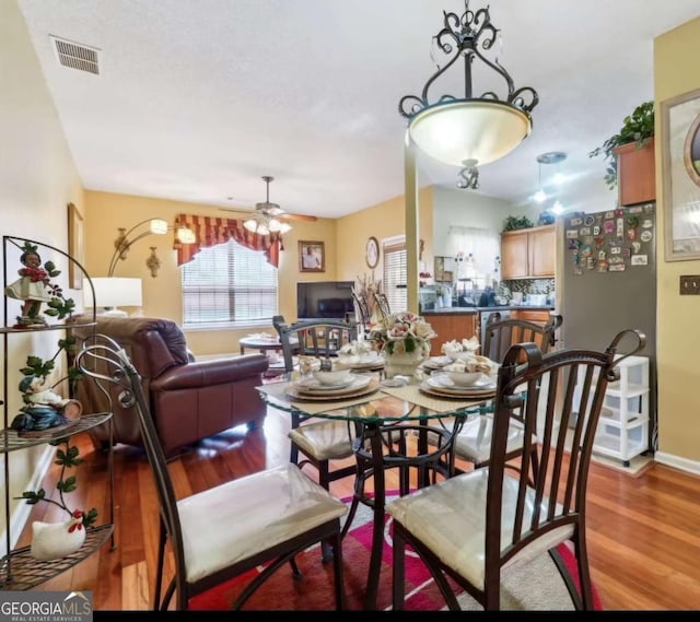 dining room featuring a ceiling fan, visible vents, light wood-style flooring, and baseboards