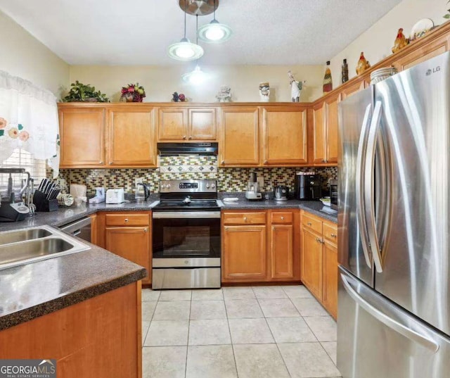 kitchen featuring under cabinet range hood, stainless steel appliances, tasteful backsplash, dark countertops, and pendant lighting