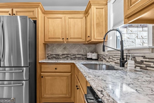 kitchen with backsplash, a sink, freestanding refrigerator, and light stone countertops