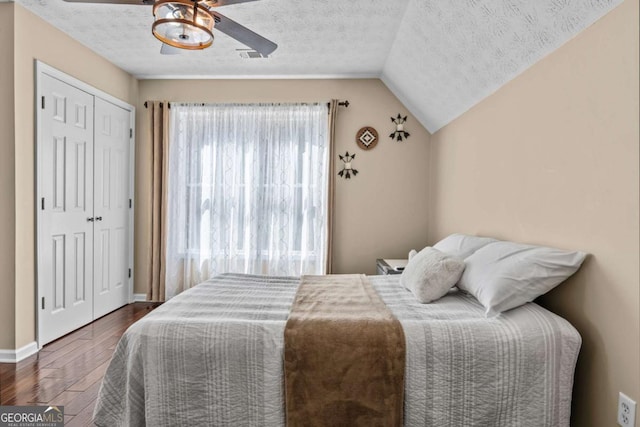 bedroom featuring a closet, dark wood-style flooring, vaulted ceiling, and a textured ceiling