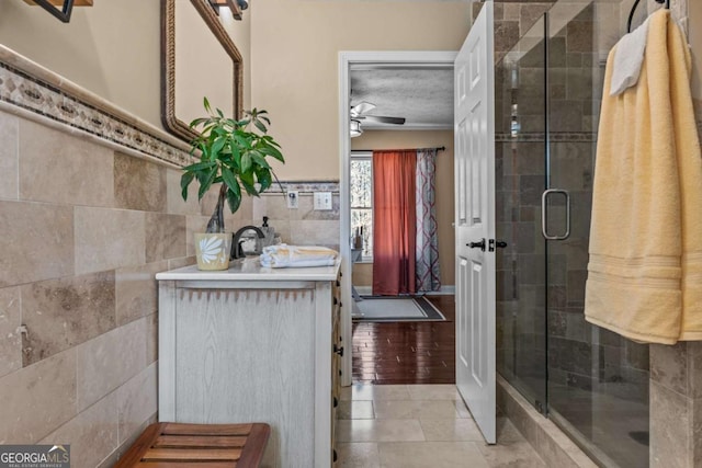 full bath with tile walls, a ceiling fan, a stall shower, a textured ceiling, and tile patterned floors