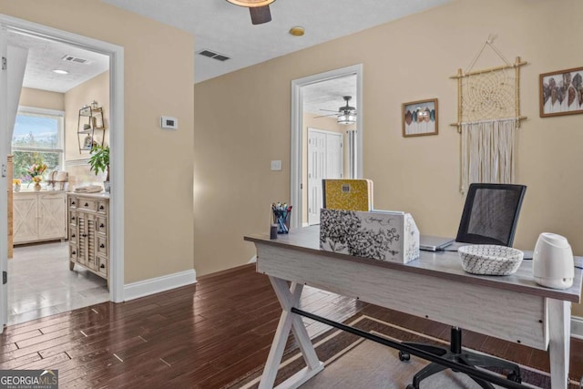 office area featuring baseboards, visible vents, a ceiling fan, and dark wood-style flooring