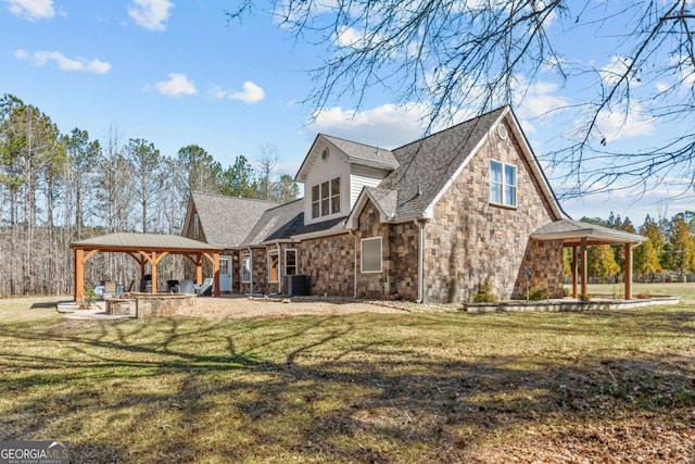 rear view of house featuring a yard, a gazebo, a patio area, cooling unit, and stone siding