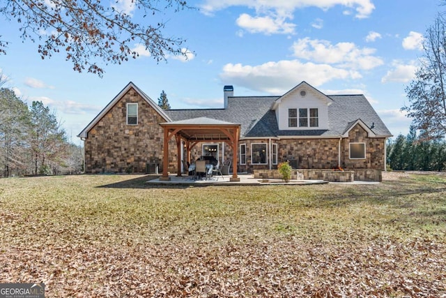 view of front of home featuring stone siding, a chimney, roof with shingles, a patio area, and a front lawn