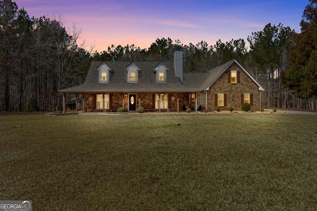 view of front of house featuring stone siding, a chimney, and a lawn