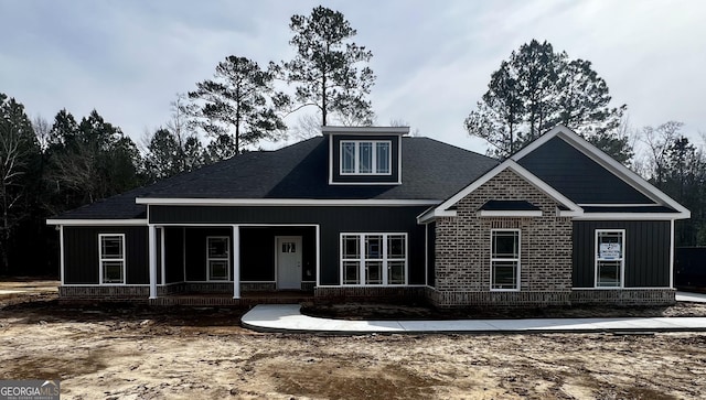 craftsman house featuring covered porch and brick siding