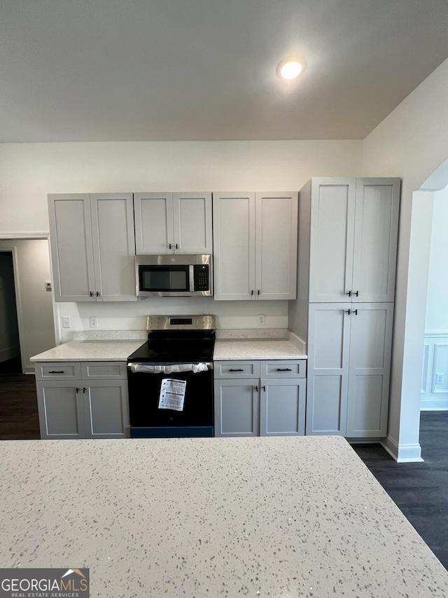 kitchen with baseboards, dark wood-style floors, appliances with stainless steel finishes, gray cabinets, and light countertops