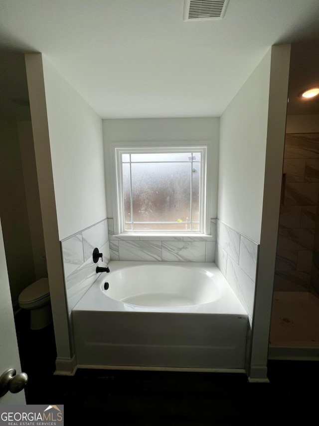 bathroom featuring toilet, visible vents, and a bath