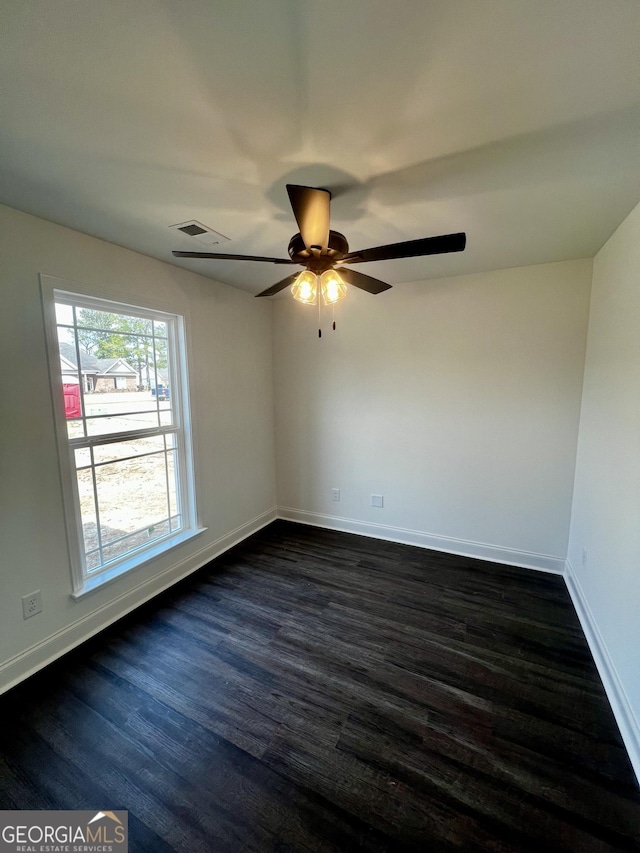 spare room with dark wood-type flooring, visible vents, baseboards, and a ceiling fan