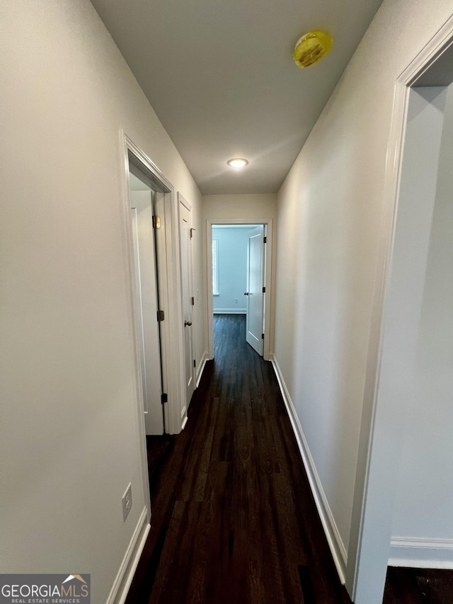 corridor featuring dark wood finished floors and baseboards