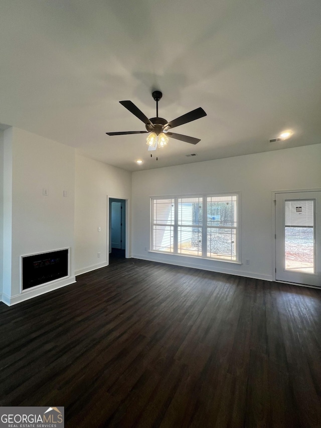 unfurnished living room featuring a fireplace, visible vents, dark wood-type flooring, a ceiling fan, and baseboards