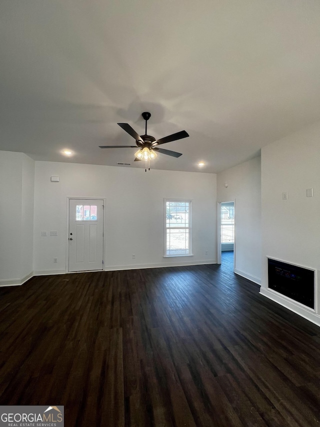 unfurnished living room with a ceiling fan, dark wood-style flooring, a fireplace, and baseboards