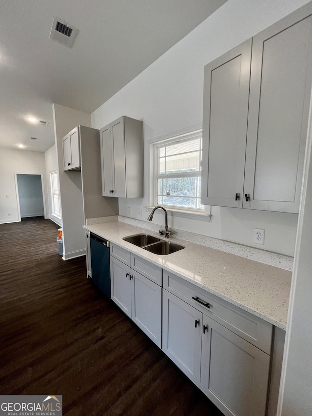 kitchen featuring dark wood-style flooring, a sink, visible vents, black dishwasher, and light stone countertops