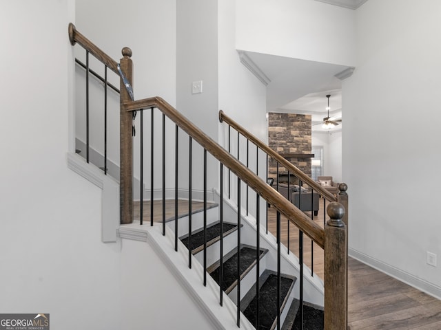 stairway with wood finished floors, a ceiling fan, and baseboards