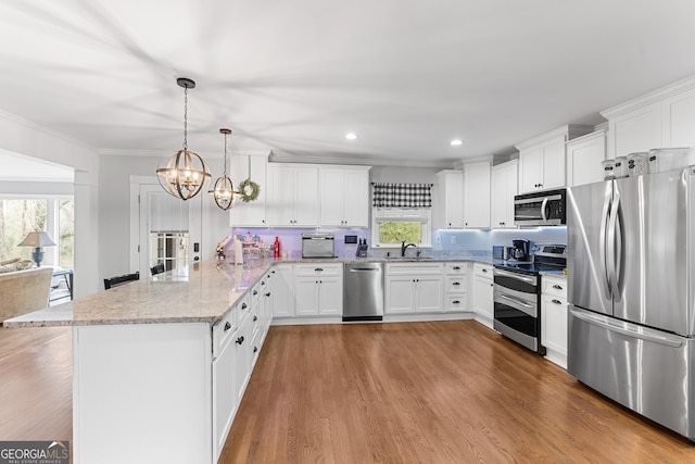 kitchen featuring stainless steel appliances, a sink, white cabinetry, light stone countertops, and pendant lighting