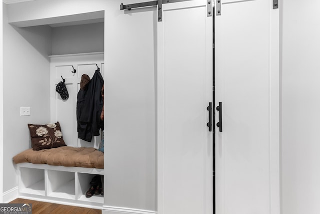 mudroom featuring a barn door, wood finished floors, and baseboards