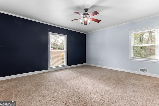 carpeted empty room featuring baseboards, visible vents, a ceiling fan, and ornamental molding