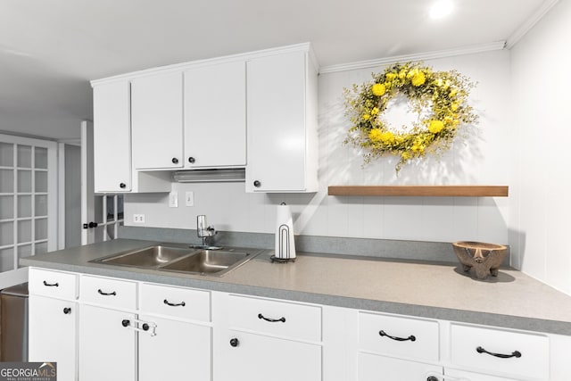 kitchen featuring dark countertops, white cabinetry, a sink, and ornamental molding