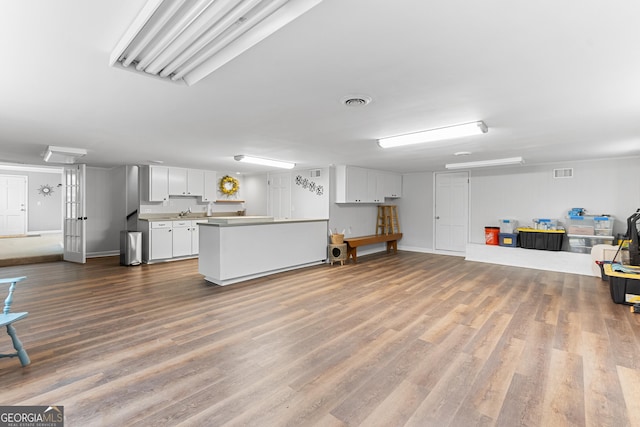 kitchen featuring white cabinets, open floor plan, light countertops, and wood finished floors