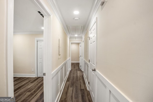 hall featuring dark wood-style floors, attic access, ornamental molding, and a decorative wall