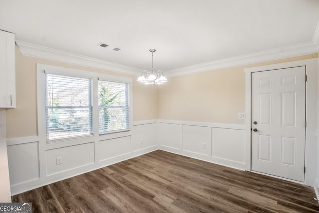 unfurnished dining area featuring an inviting chandelier, ornamental molding, dark wood-type flooring, and a wainscoted wall