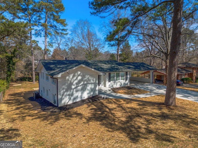 view of home's exterior featuring concrete driveway, a yard, and an attached carport