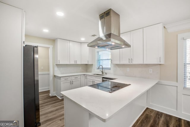 kitchen featuring light countertops, freestanding refrigerator, white cabinets, and island range hood