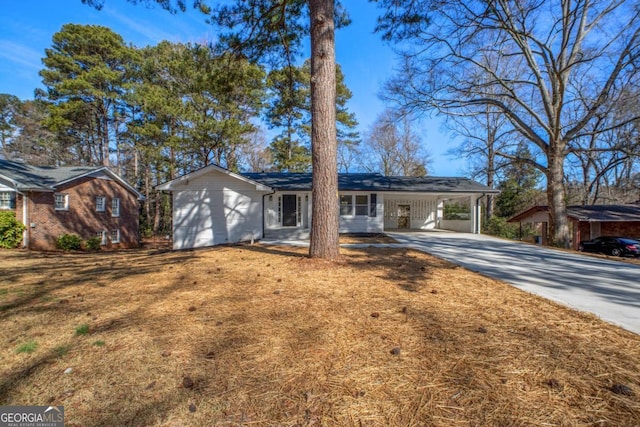 single story home with concrete driveway, a carport, and a front lawn