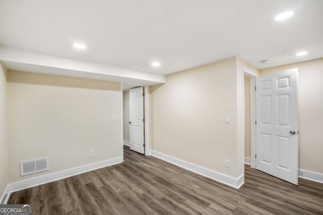 finished basement featuring dark wood-style floors, visible vents, and baseboards