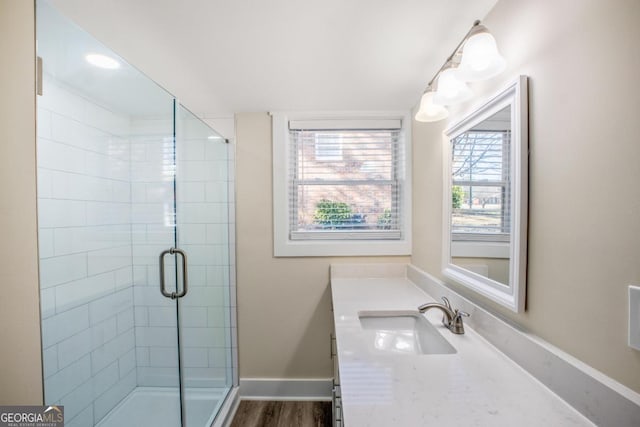 full bathroom with wood finished floors, a shower stall, vanity, and baseboards