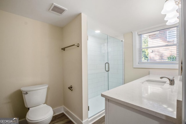 bathroom featuring visible vents, toilet, a shower stall, wood finished floors, and baseboards