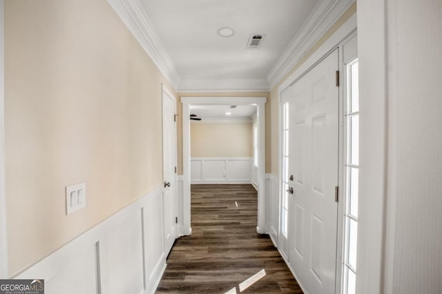 hall with visible vents, a wainscoted wall, ornamental molding, dark wood-style flooring, and a decorative wall