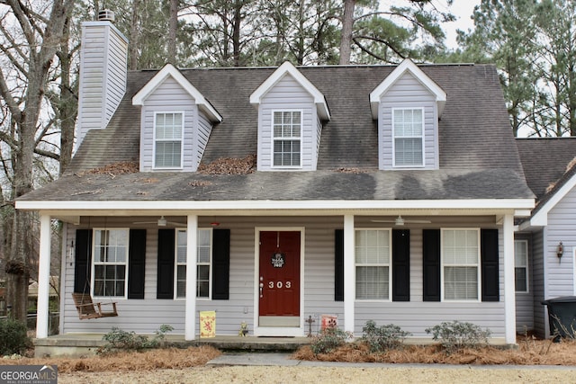 cape cod-style house with covered porch, a shingled roof, and a chimney