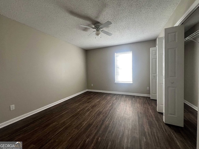 unfurnished bedroom with a textured ceiling, ceiling fan, dark wood finished floors, and baseboards