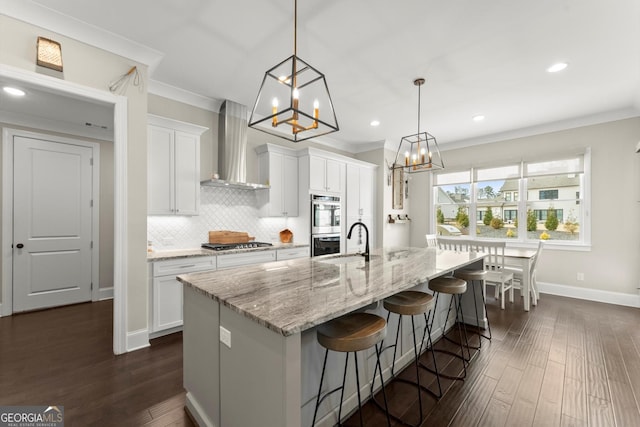 kitchen featuring wall chimney exhaust hood, dark wood finished floors, white cabinets, a chandelier, and stainless steel appliances