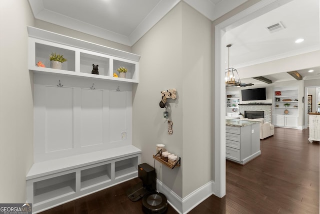 mudroom featuring visible vents, baseboards, ornamental molding, dark wood finished floors, and a glass covered fireplace