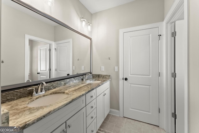 bathroom with a sink, tile patterned floors, double vanity, and baseboards