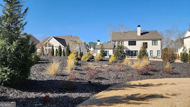 rear view of property featuring a chimney and a residential view