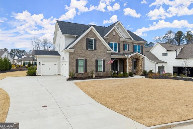 view of front of house featuring a shingled roof, an attached garage, brick siding, a front lawn, and driveway