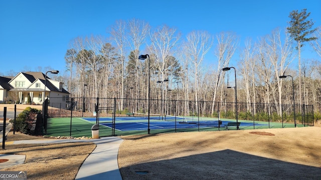 view of basketball court with a tennis court and fence