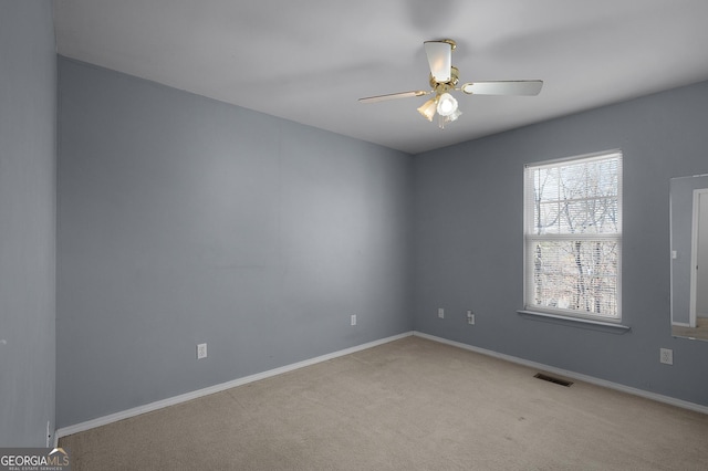 carpeted empty room with baseboards, visible vents, and a ceiling fan