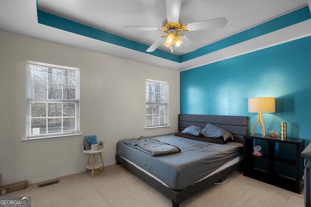 bedroom with baseboards, visible vents, ceiling fan, a tray ceiling, and carpet flooring